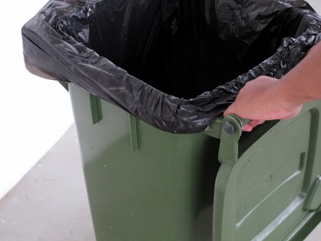 Worker in PPE checking a skip and vehicle load before departure